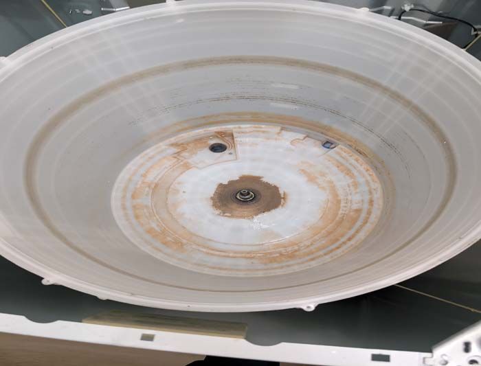 Inside view of a washing machine drum, showing brown stains and wear on the central base.