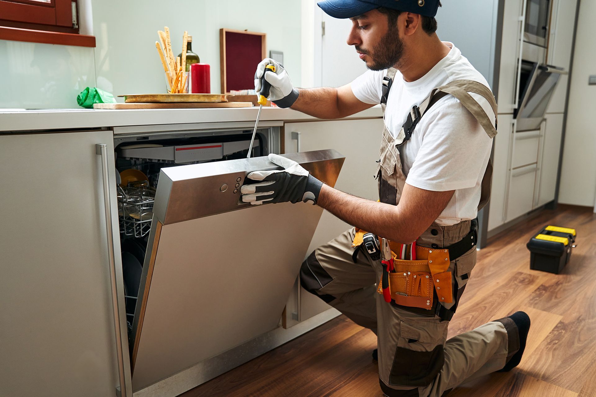 A man is fixing a dishwasher in a kitchen.