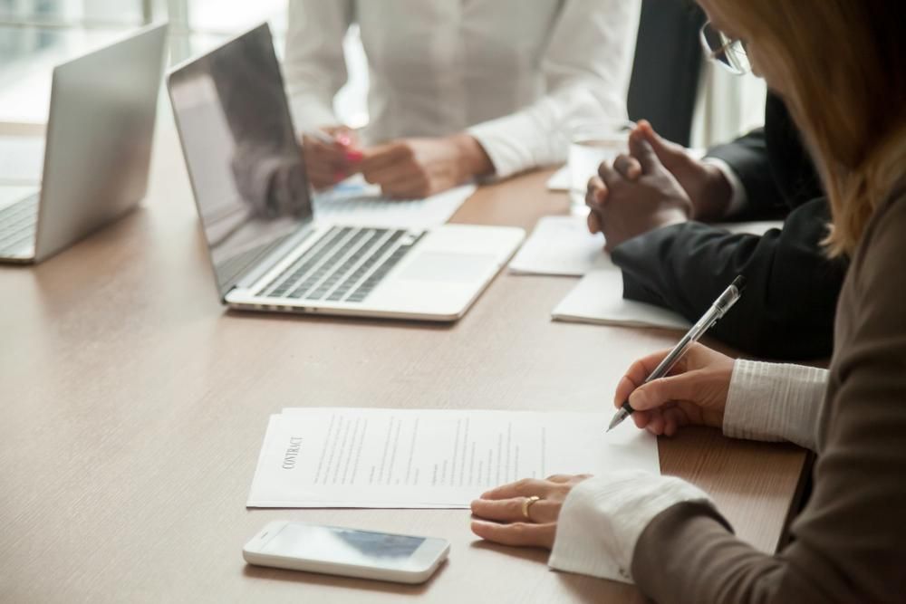 A group of people are sitting at a table with laptops and papers — Coast & Country Insurance Consultants Pty Ltd In Central Coast, NSW