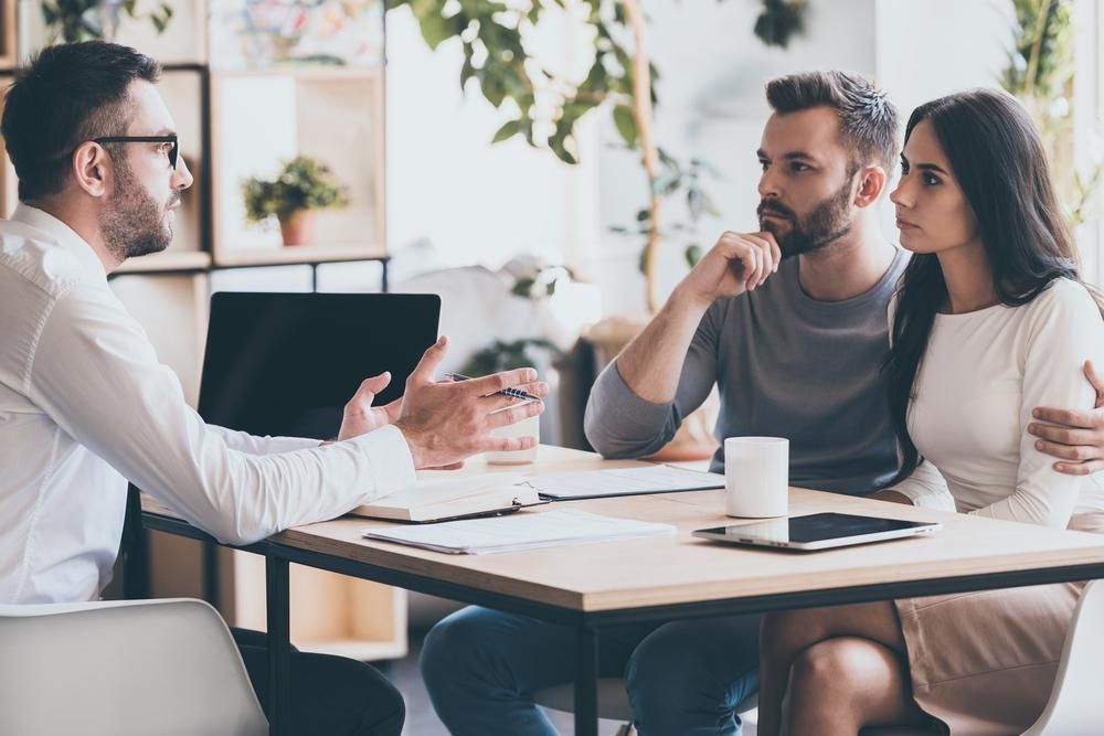 A Man Is Sitting At A Table Talking To A Couple — Coast & Country Insurance Consultants Pty Ltd In Central Coast, NSW