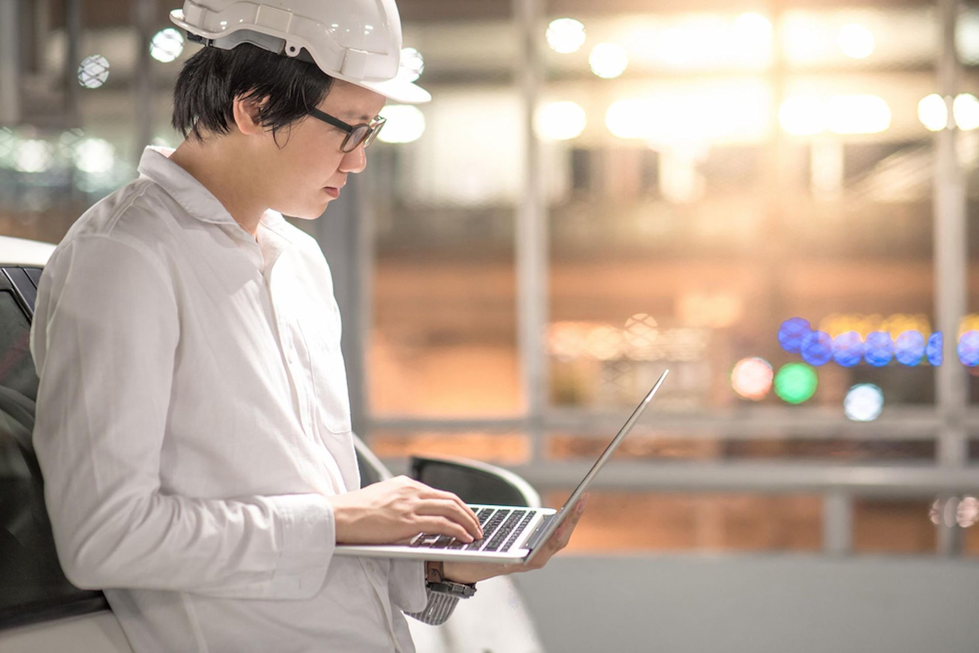a Man Wearing a Hard Hat is Using a Laptop Computer — Coast & Country Insurance Consultants Pty Ltd In Central Coast, NSW