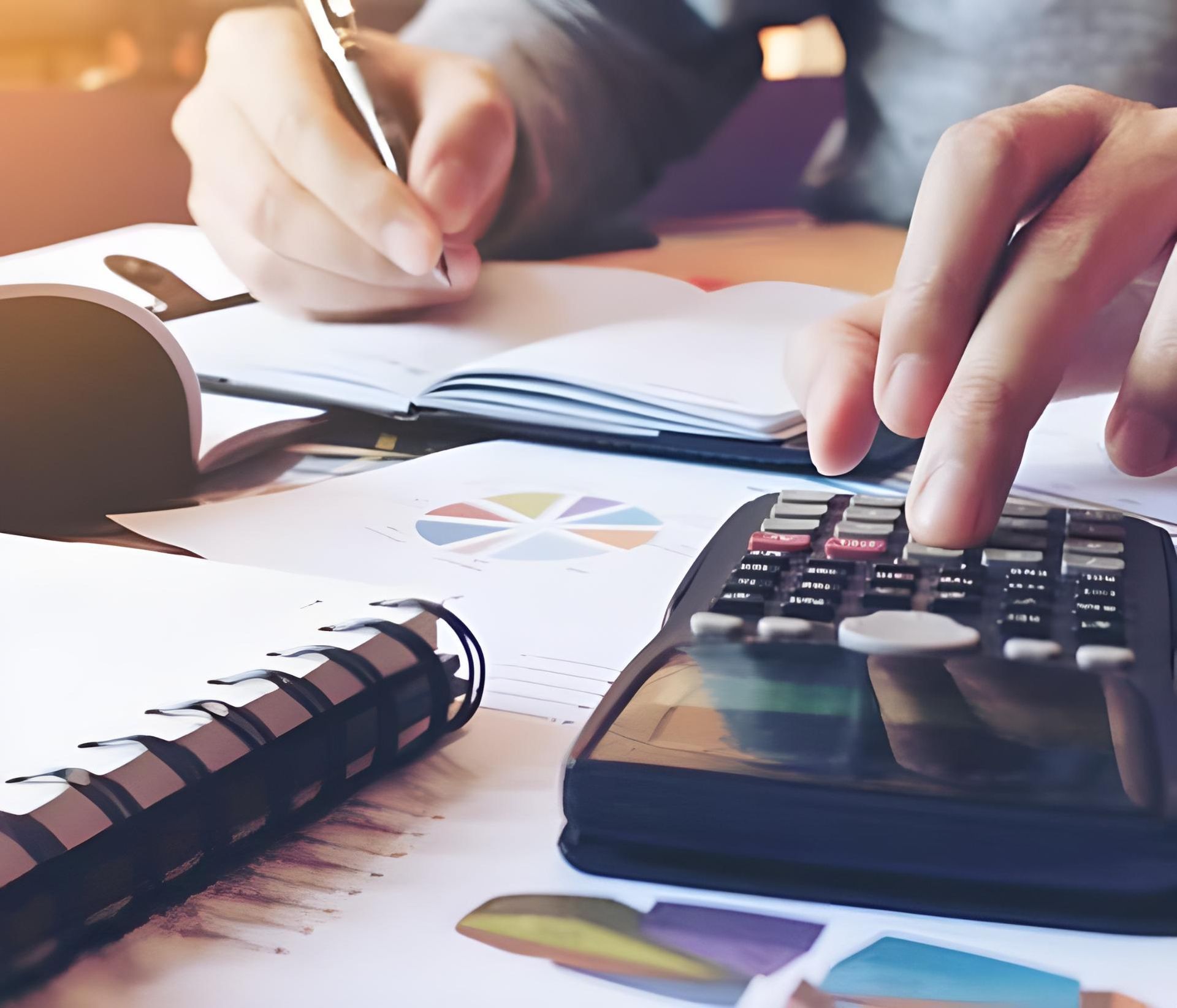 A person is using a calculator while writing in a notebook — Coast & Country Insurance Consultants Pty Ltd In Central Coast, NSW
