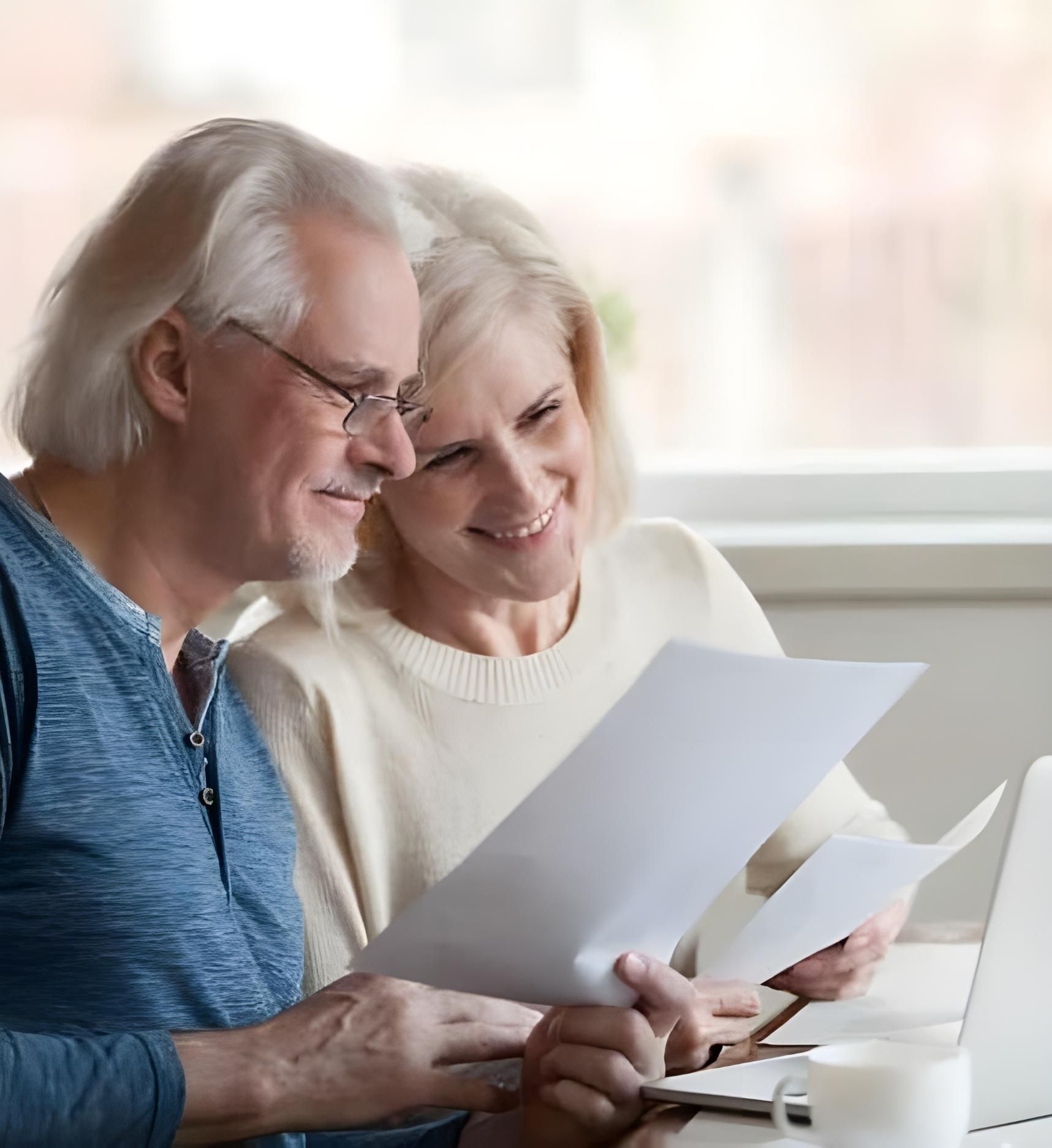 A Man And A Woman Are Sitting At A Table Looking At Papers — Coast & Country Insurance Consultants Pty Ltd In Central Coast, NSW