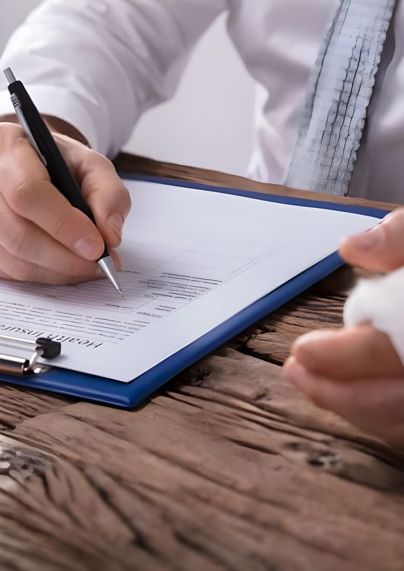 A Person Is Writing On A Clipboard With A Pen — Coast & Country Insurance Consultants Pty Ltd In Central Coast, NSW
