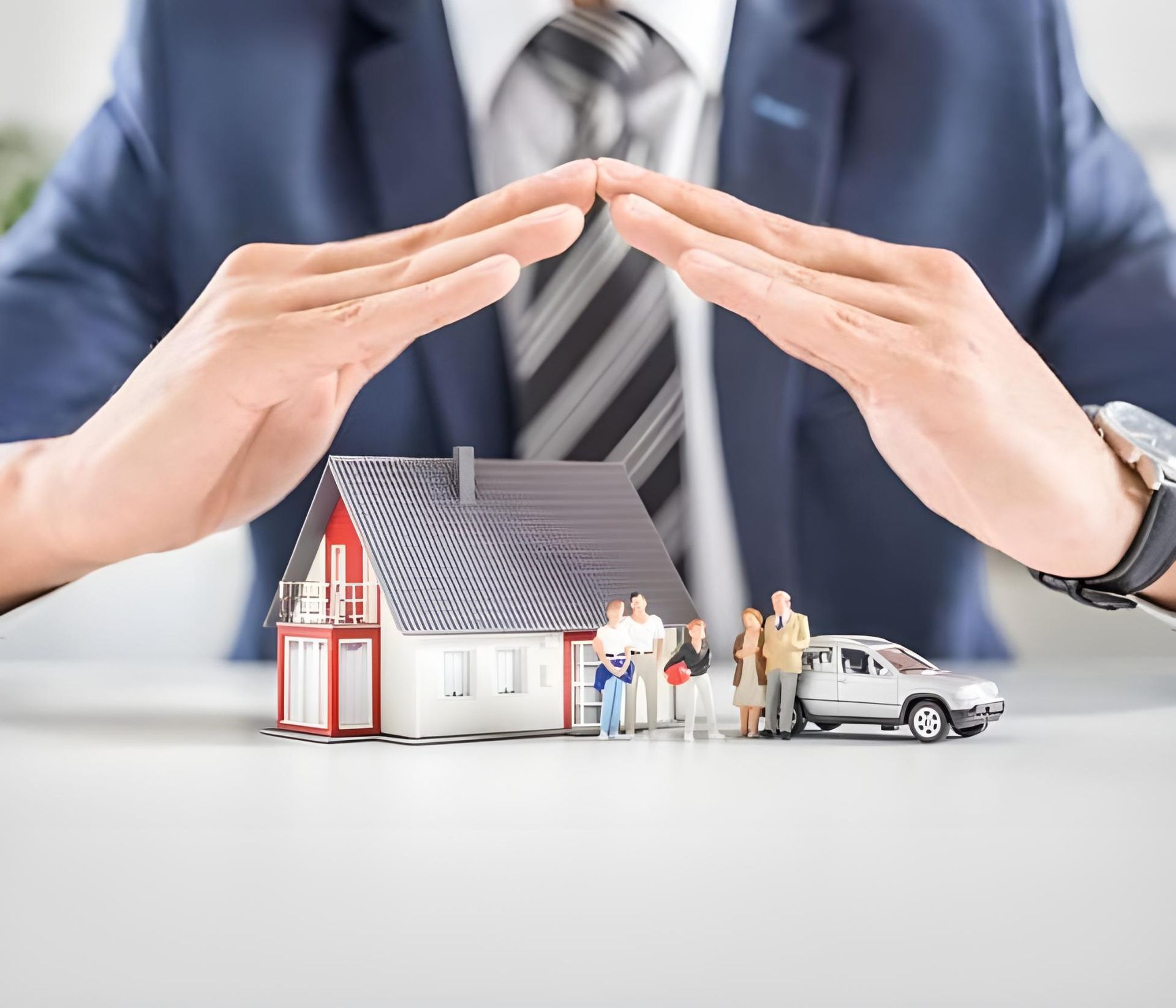 A Man In A Suit And Tie Is Covering A Small House With His Hands — Coast & Country Insurance Consultants Pty Ltd In Central Coast, NSW