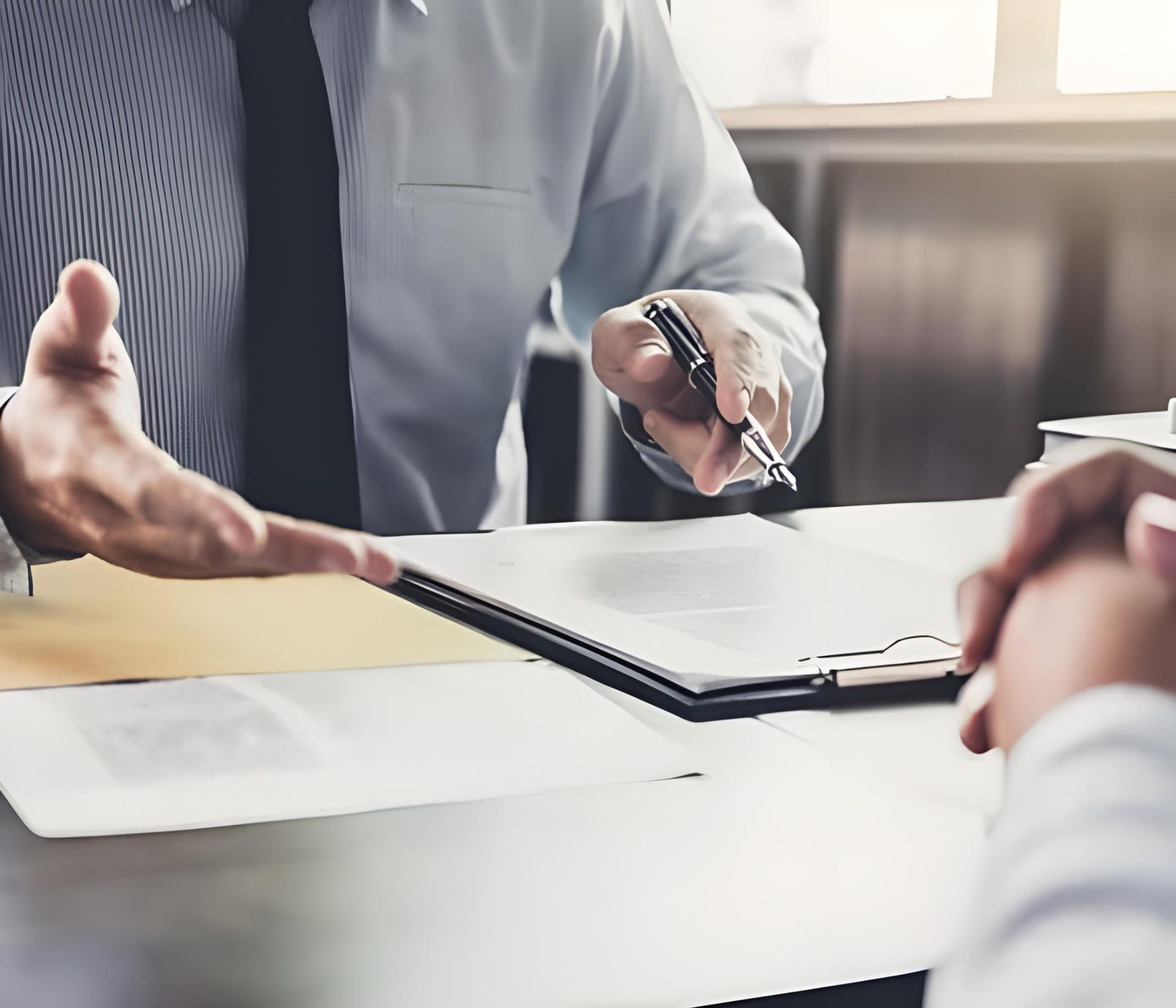 A man is sitting at a table holding a pen and talking to another man -Coast & Country Insurance Consultants Pty Ltd In Central Coast, NSW
