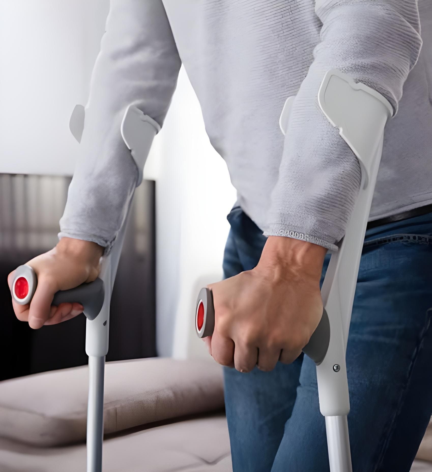 A Man Is Using Crutches To Walk In A Living Room — Coast & Country Insurance Consultants Pty Ltd In Central Coast, NSW