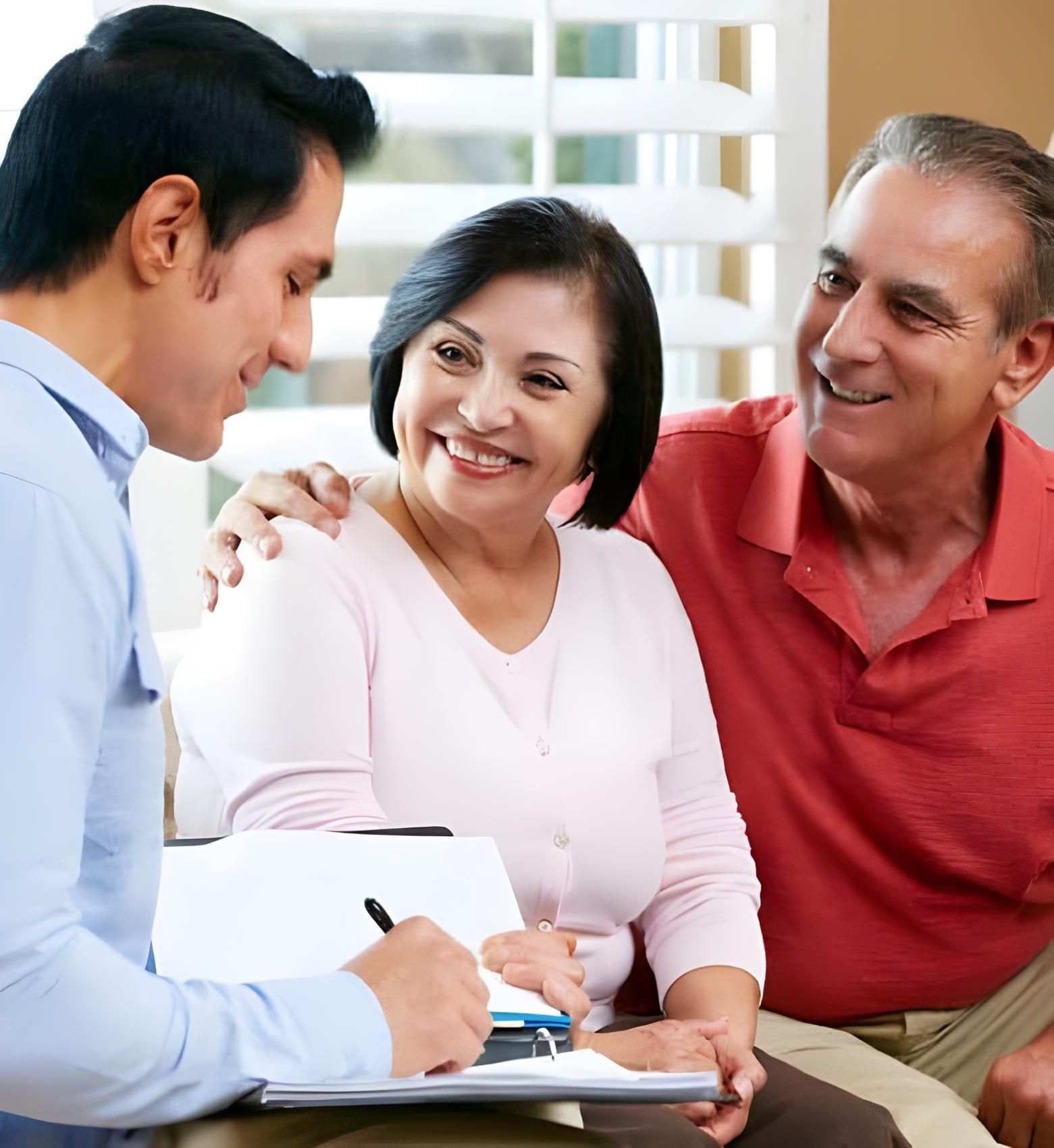 Two Men And A Woman Are Sitting On A Couch With A Man Writing On A Clipboard — Coast & Country Insurance Consultants Pty Ltd In Central Coast, NSW