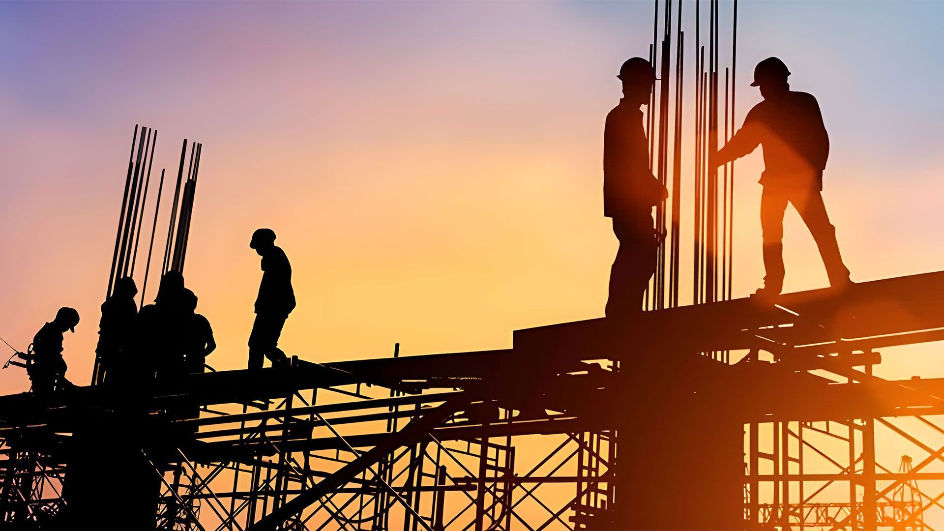 A group of construction workers are working on a construction site at sunset — Coast & Country Insurance Consultants Pty Ltd In Central Coast, NSW
