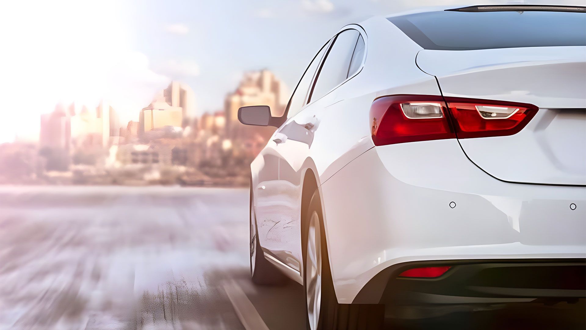 A white car is driving down a road with a city in the background — Coast & Country Insurance Consultants Pty Ltd In Central Coast, NSW