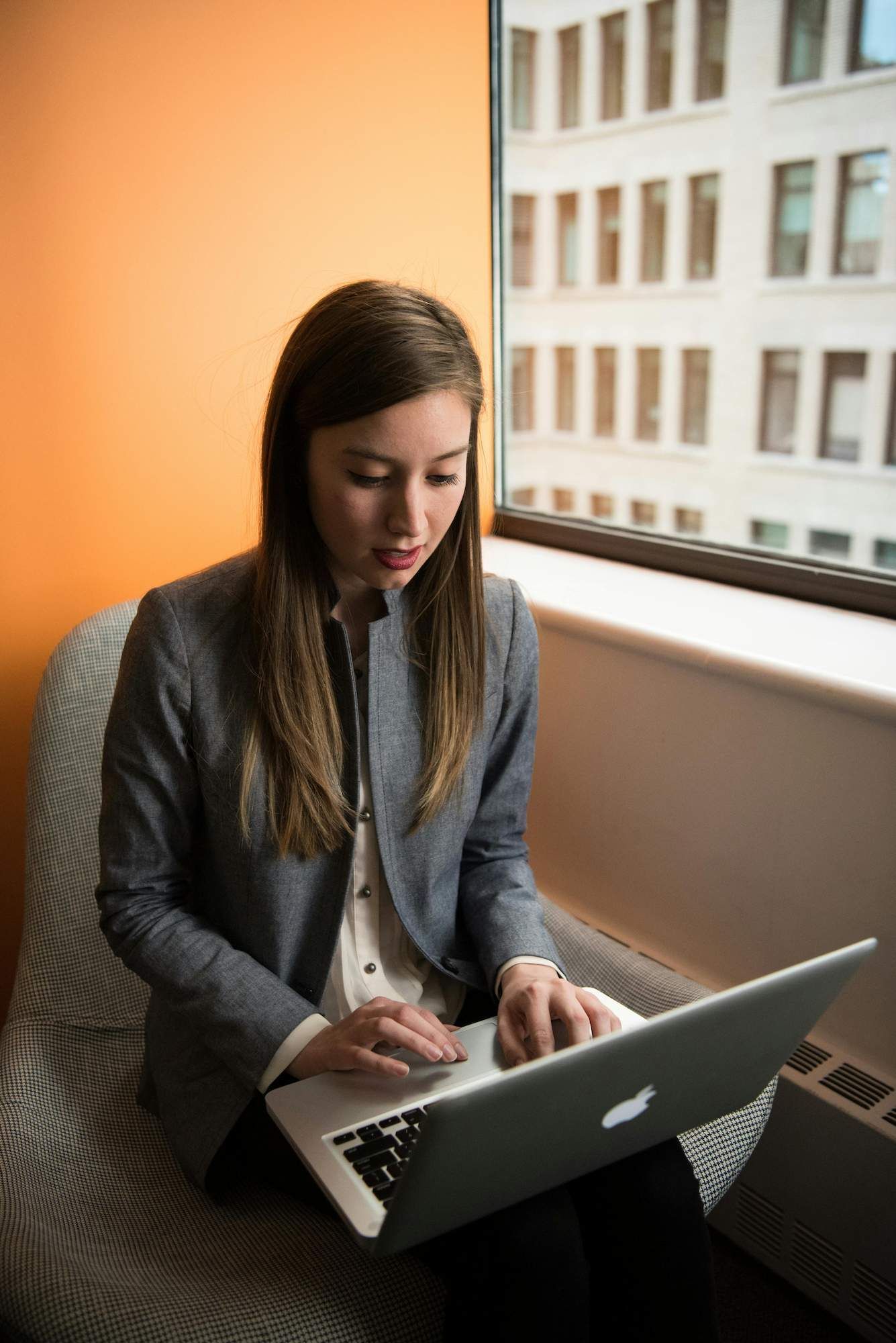 a Woman is Sitting in a Chair Using a Laptop Computer — Coast & Country Insurance Consultants Pty Ltd In Central Coast, NSW