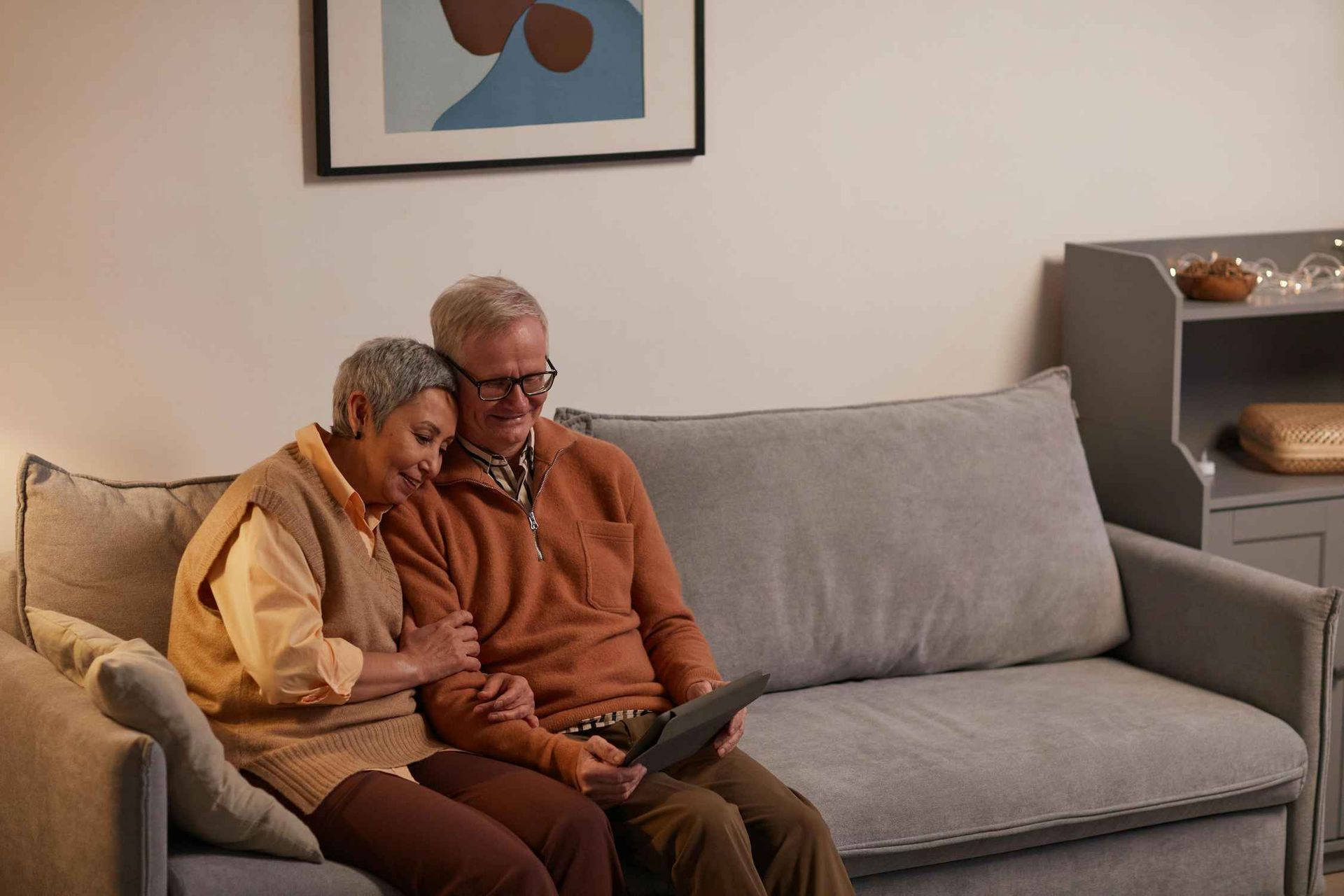 an Elderly Couple is Sitting on a Couch Looking at a Tablet — Coast & Country Insurance Consultants Pty Ltd In Central Coast, NSW