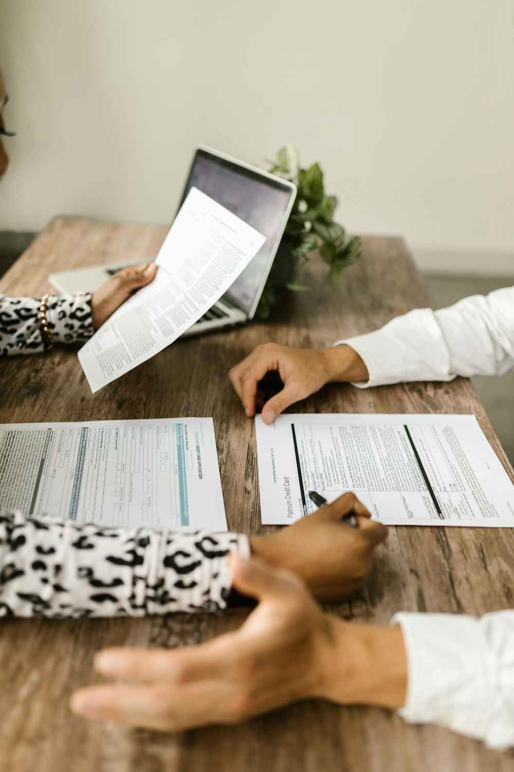 Two People Are Sitting at a Table With Papers and a Laptop — Coast & Country Insurance Consultants Pty Ltd In Central Coast, NSW