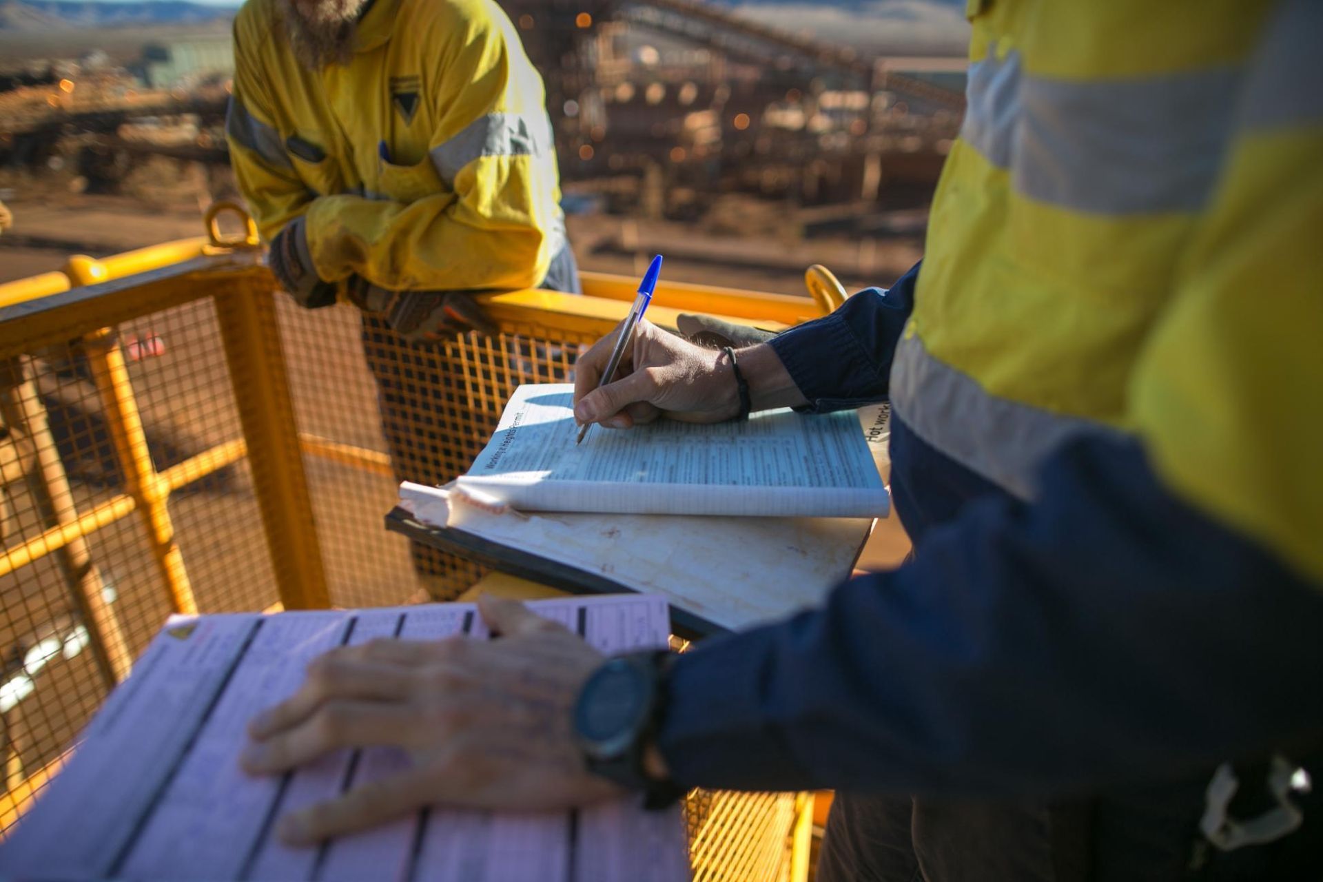a Man is Writing on a Piece of Paper While Another Man Looks on — Coast & Country Insurance Consultants Pty Ltd In Central Coast, NSW