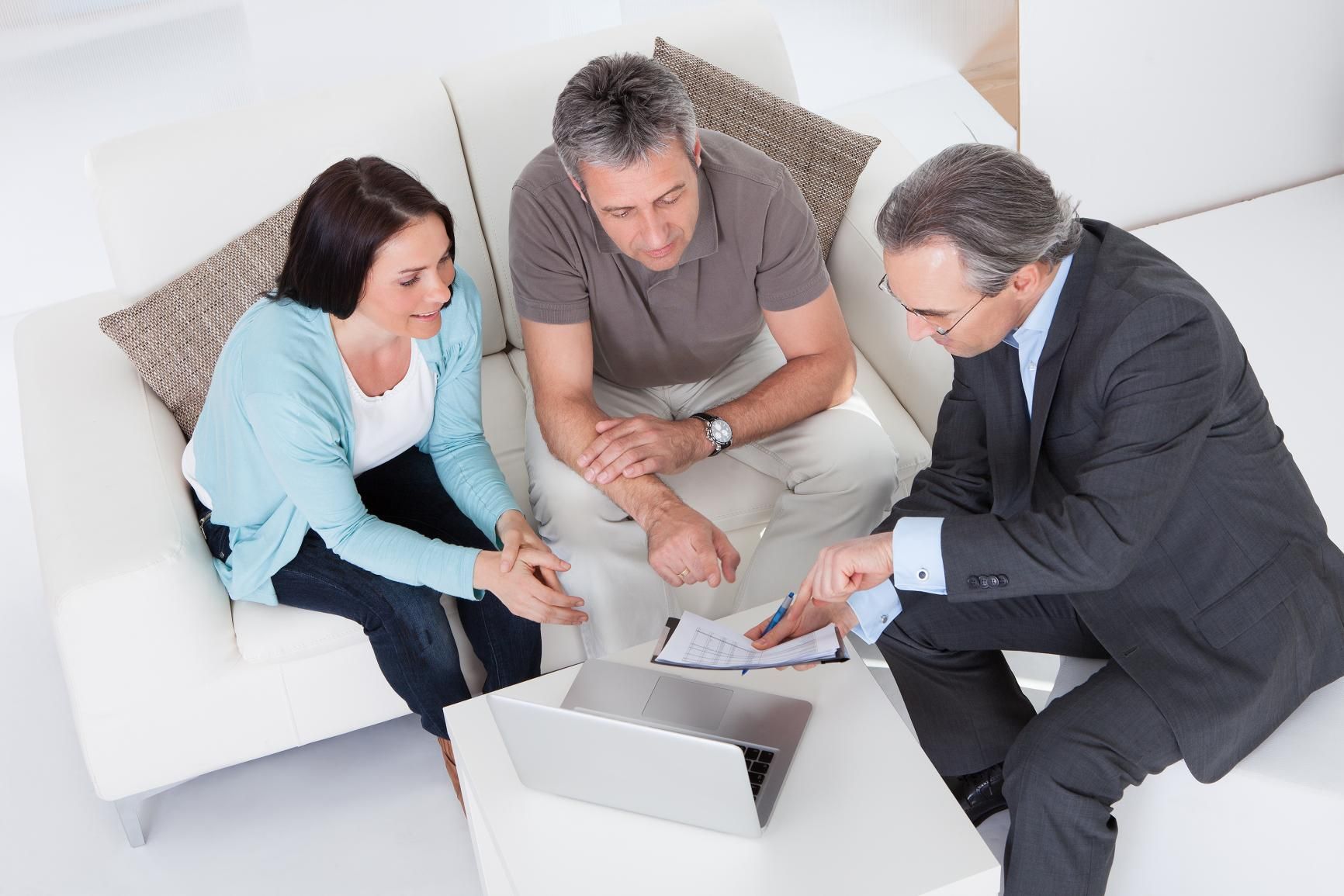 a Man and Woman Are Sitting on a Couch Talking to a Man in a Suit — Coast & Country Insurance Consultants Pty Ltd In Central Coast, NSW