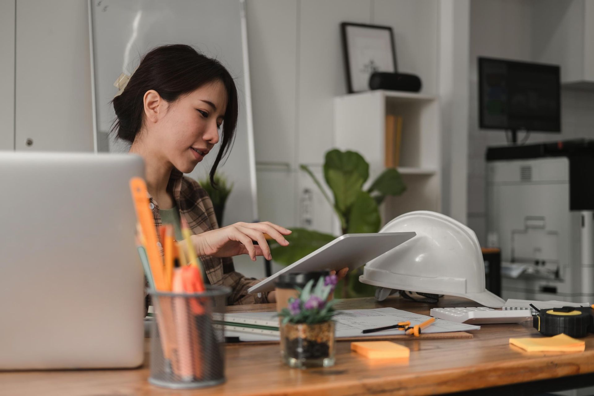 a Woman is Sitting at a Desk Using a Tablet Computer — Coast & Country Insurance Consultants Pty Ltd In Central Coast, NSW