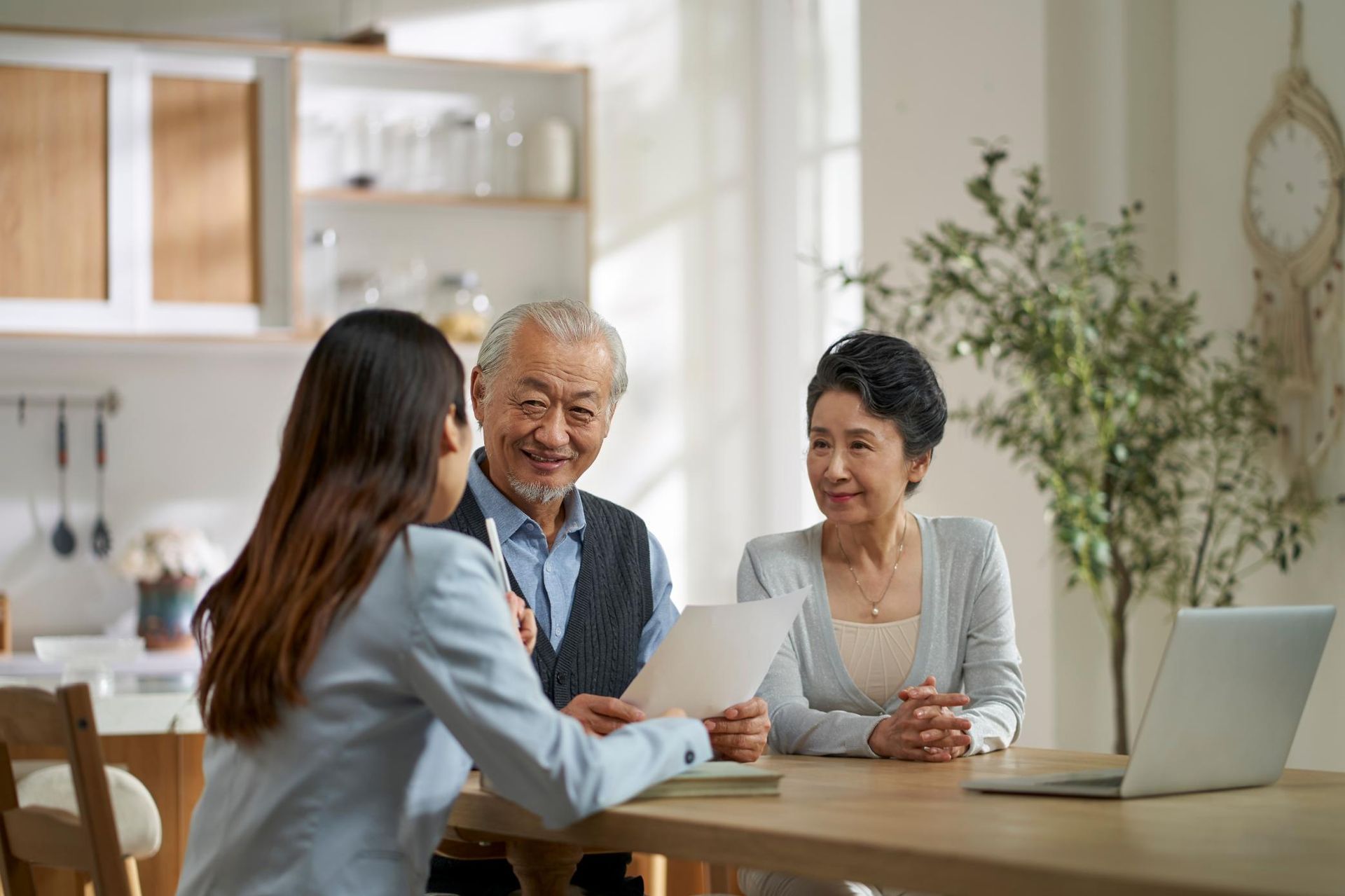 a Woman is Sitting at a Table Talking to an Elderly Couple — Coast & Country Insurance Consultants Pty Ltd In Central Coast, NSW