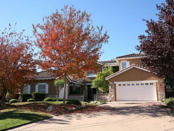 A large house with a garage and trees in front of it