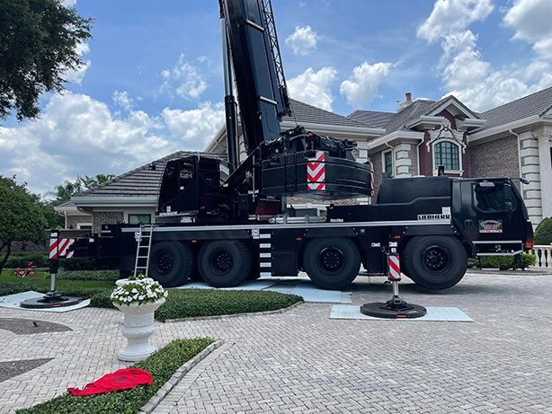 A large crane is parked in front of a house.