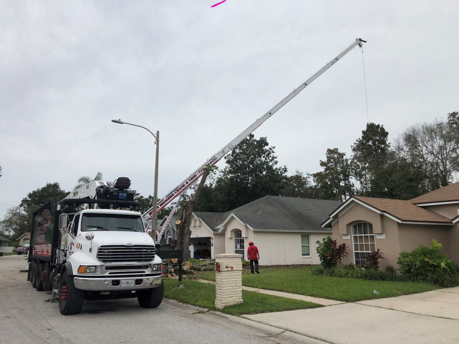 A truck with a crane on top of it is parked in front of a house.