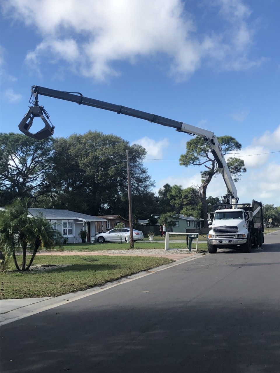 A truck with a crane attached to it is parked on the side of the road.