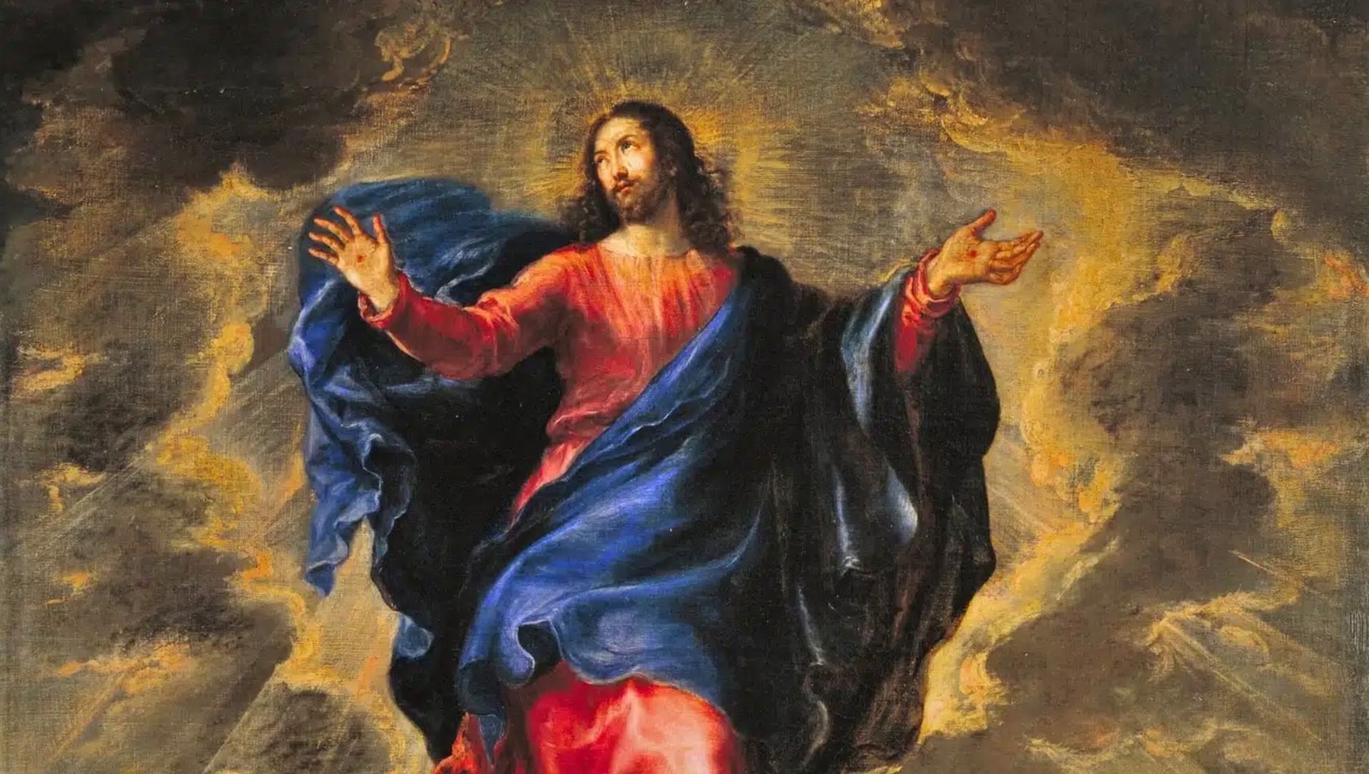 Jesus in red and blue robes, arms raised, surrounded by golden light, cloudy background.