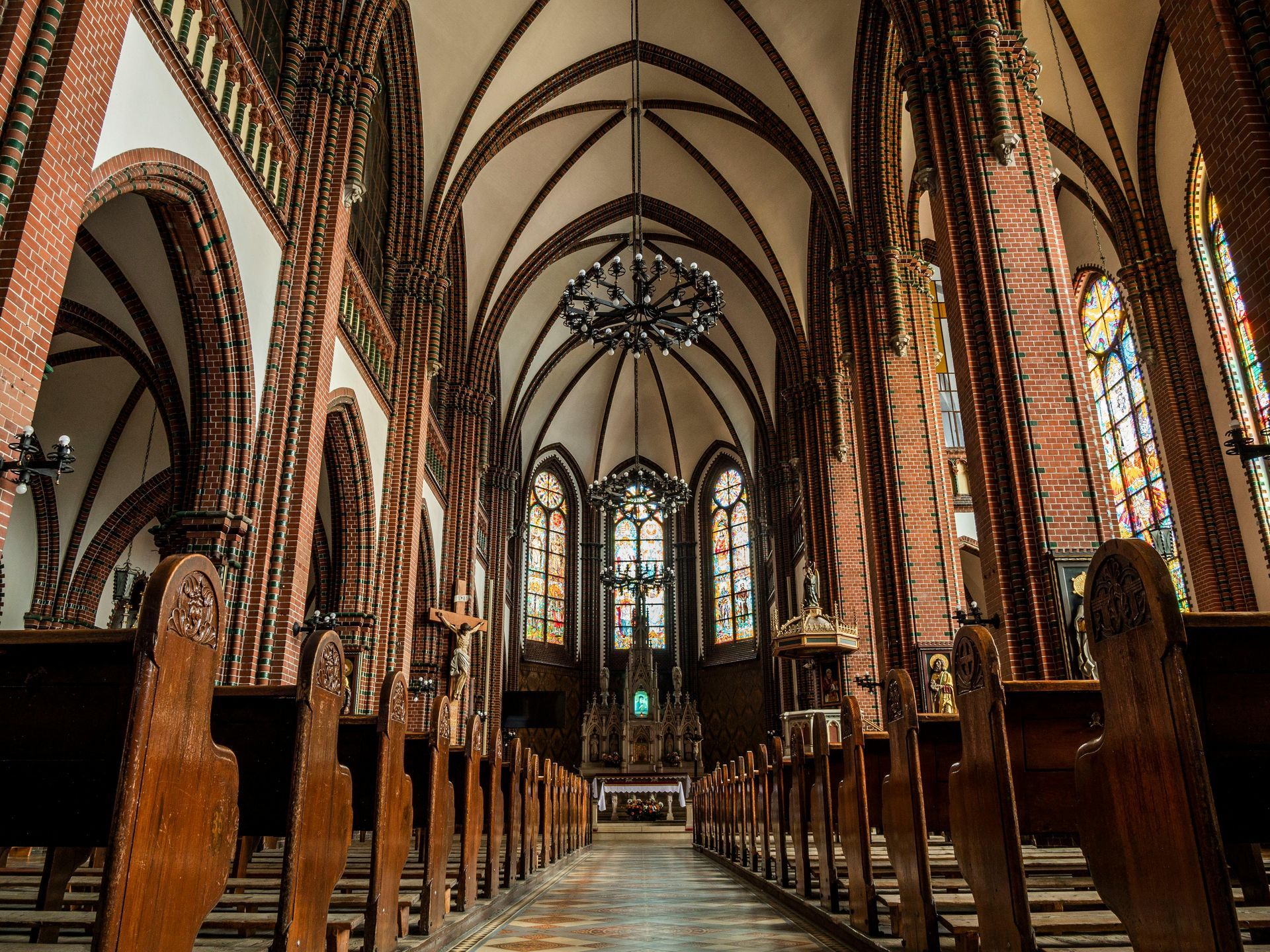 Interior of a bright and elegant church sanctuary with stained glass windows, wooden pews, and sunli