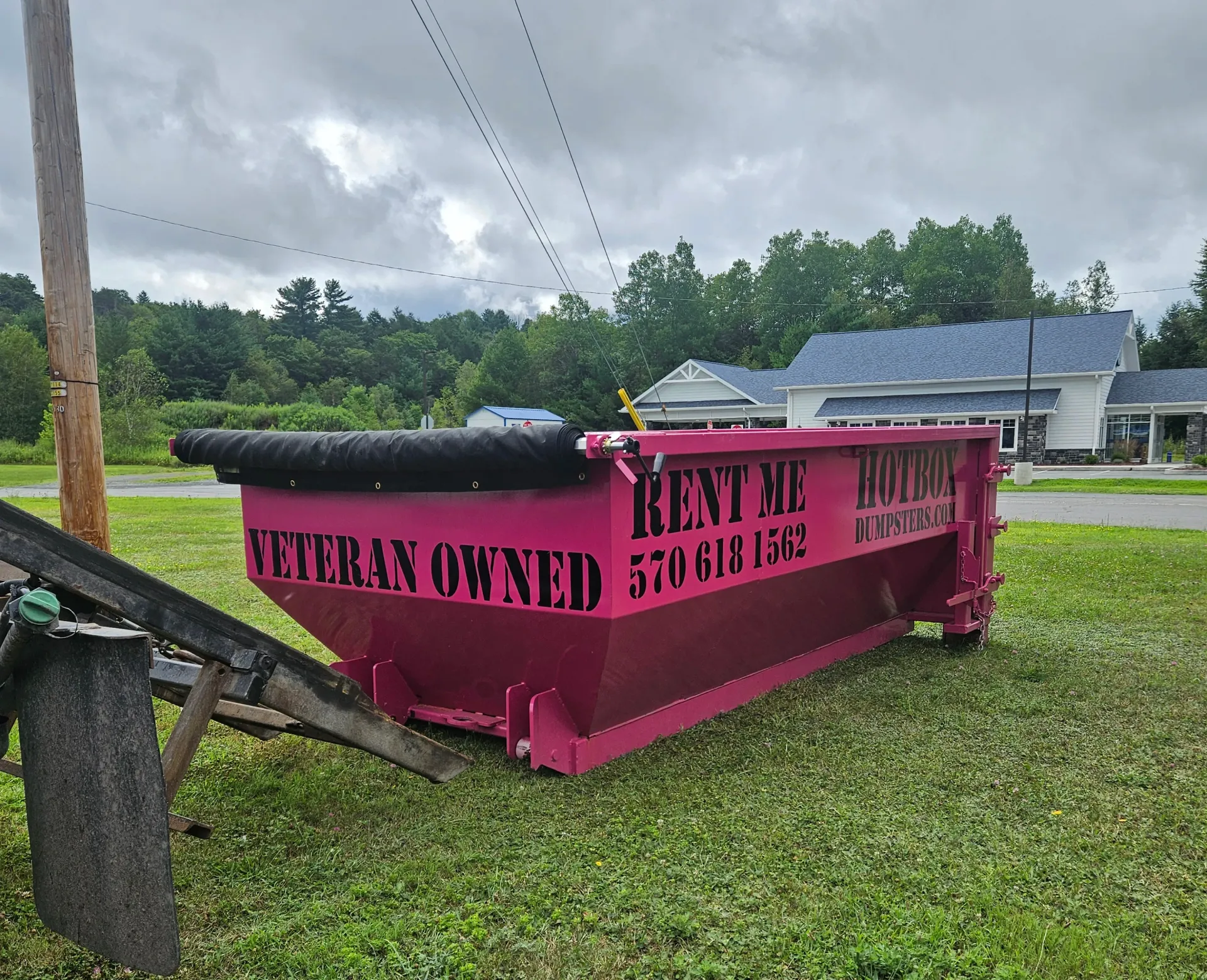 A dumpster is being towed by a dump truck in a driveway.