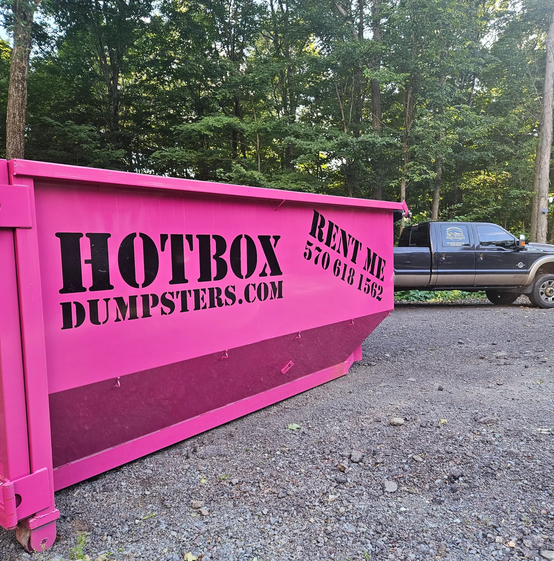 A green dumpster is parked in front of a house.