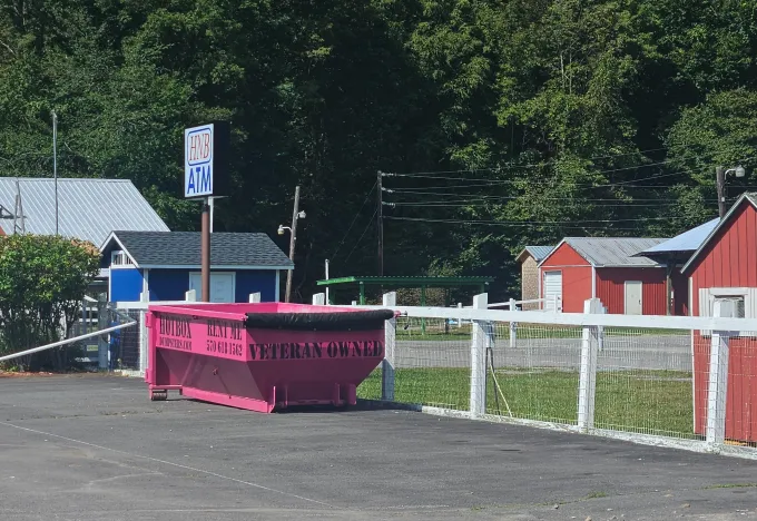 A green dumpster is parked in front of a house.