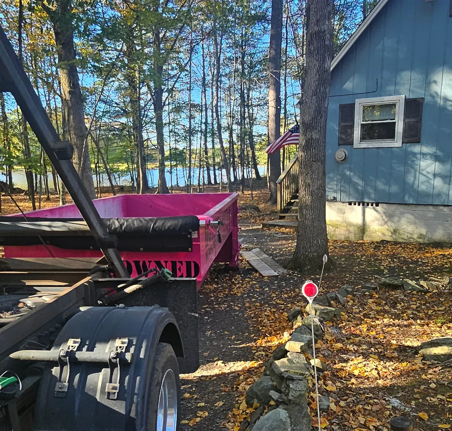 A green dumpster is parked in front of a house.
