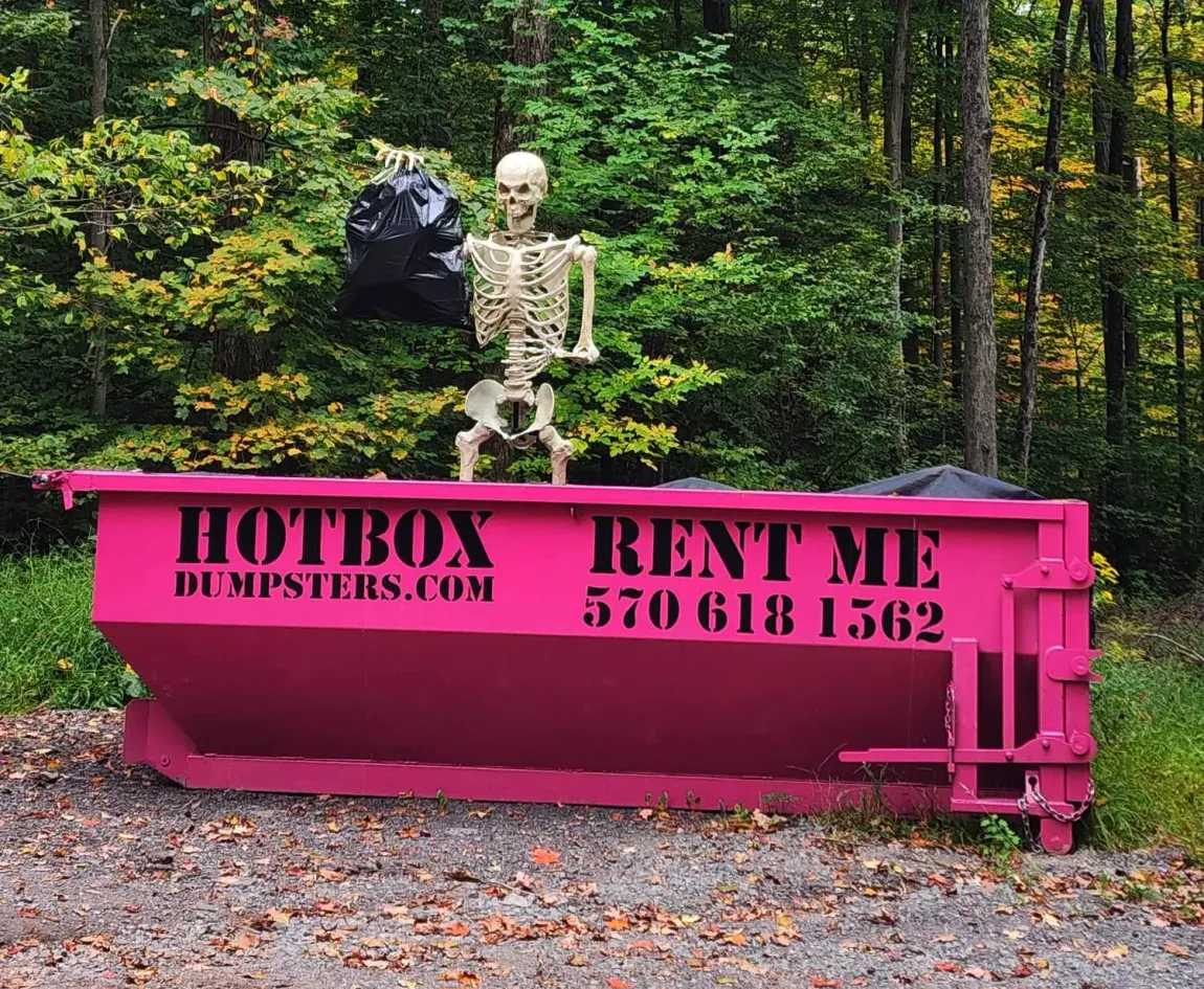 A green dumpster is sitting next to a truck in a parking lot.