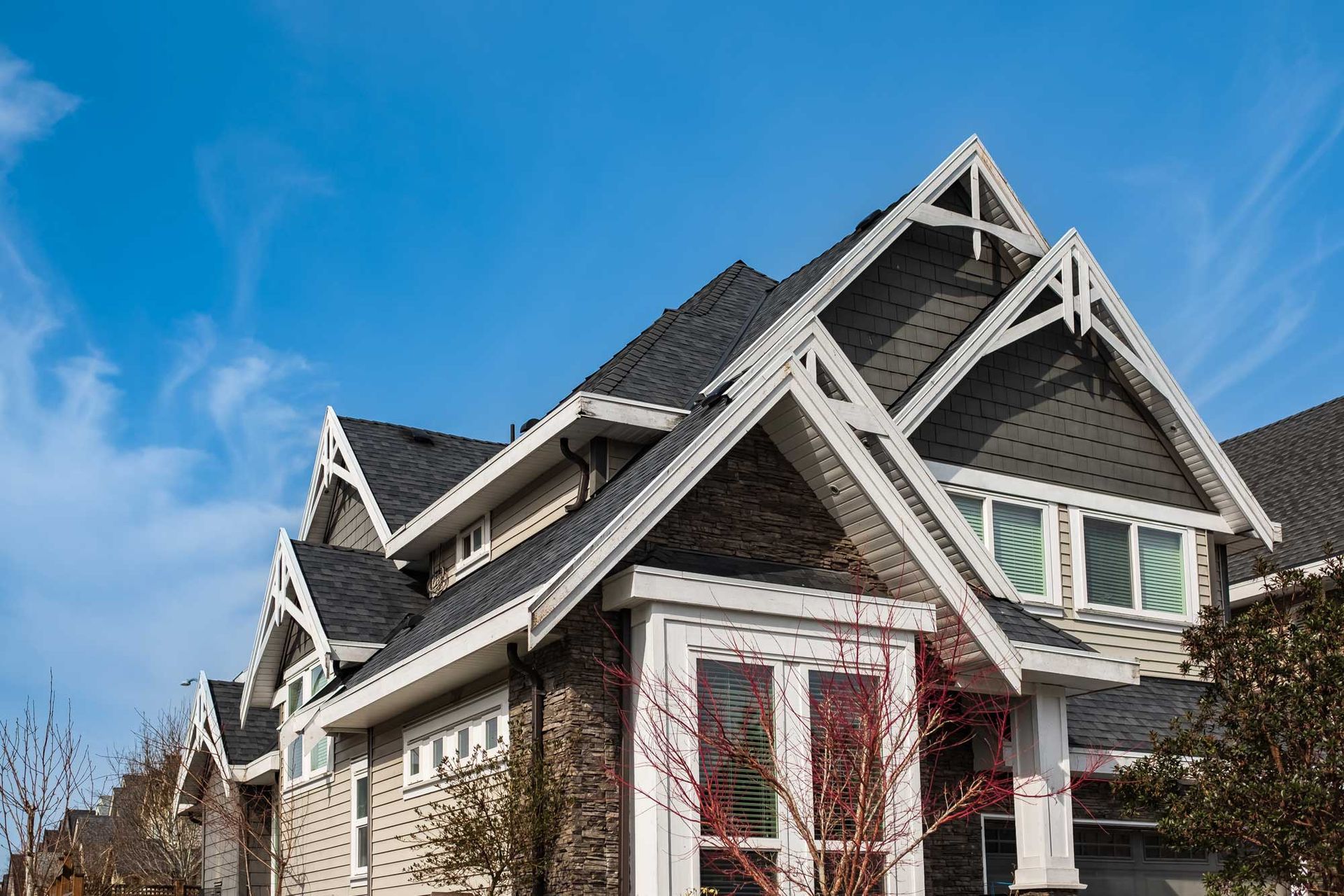 Row of multi-story houses with dark gray roofs, blue sky.