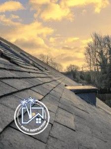 Gray slate roof with chimney, set against a sunset sky. Gray slate roof with chimney, set against a sunset sky.