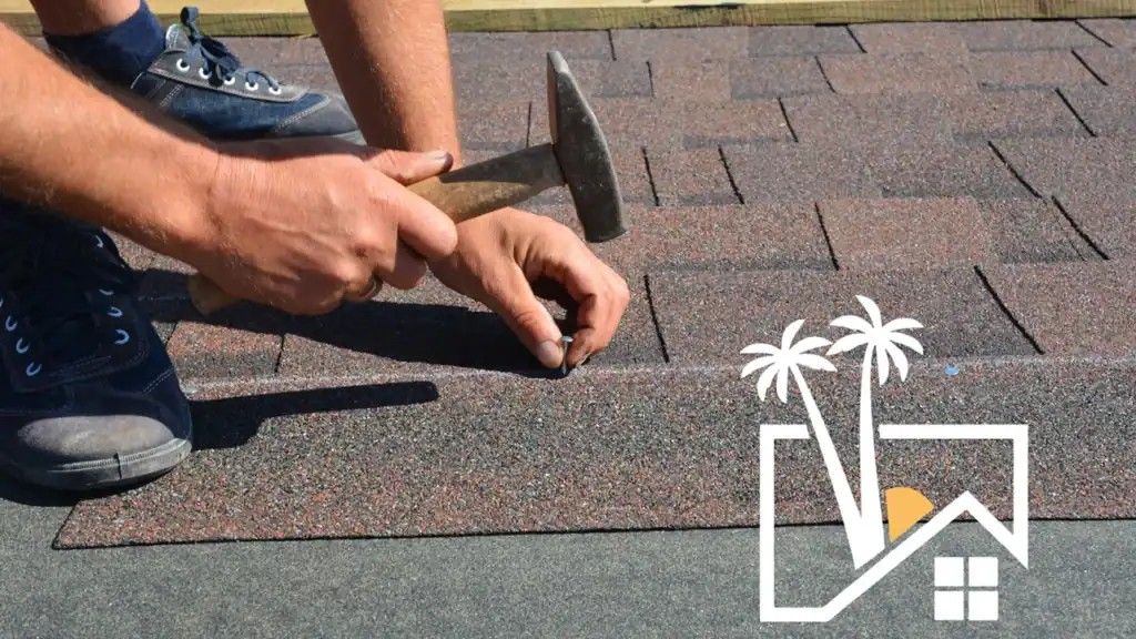 Person hammering roofing shingle, brown and gray, on a roof. Person hammering roofing shingle, brown and gray, on a roof.