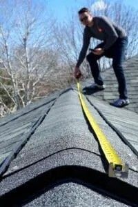 Person hammering a nail into a brown shingle on a roof. Person hammering a nail into a brown shingle on a roof.
