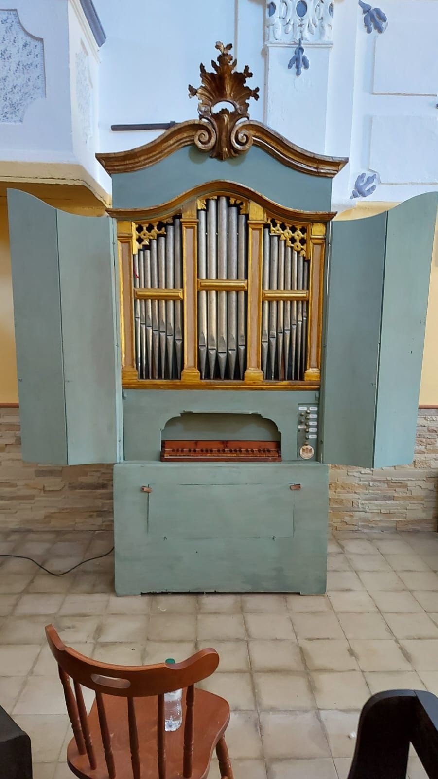 un organo è seduto in una chiesa accanto a una sedia .