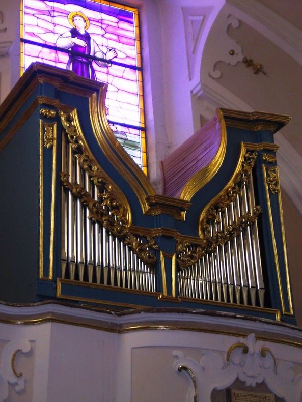 un organo in una chiesa con una vetrata sullo sfondo