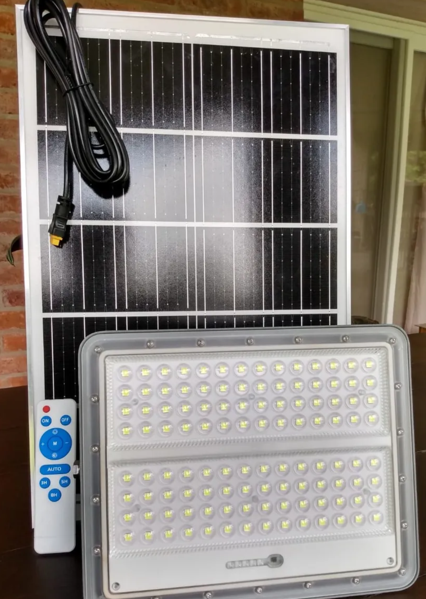 Un panel solar y un control remoto están sobre una mesa.