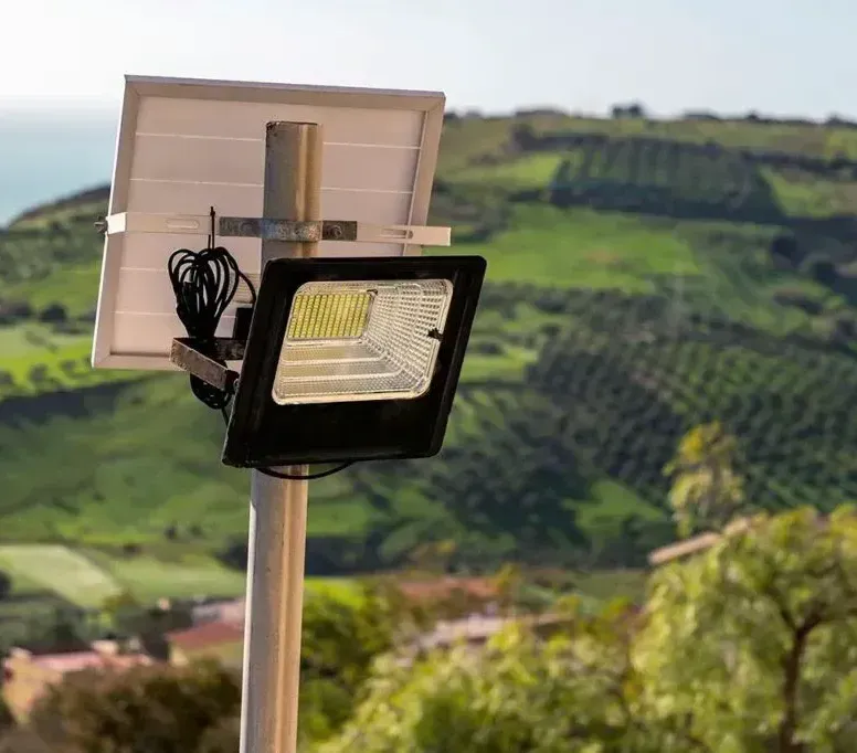 Un reflector con un panel solar conectado está ubicado encima de un poste.