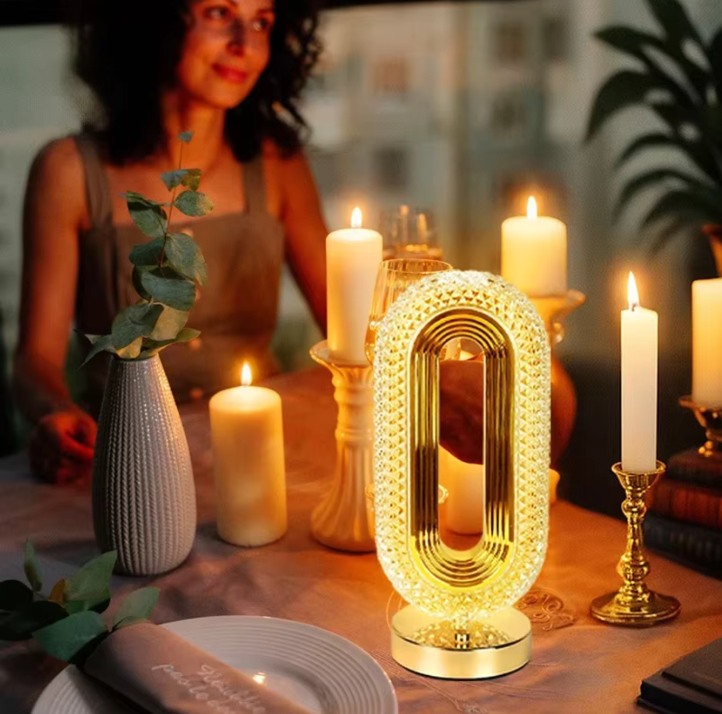 Una mujer está sentada en una mesa con velas y una luz en forma del número 0.