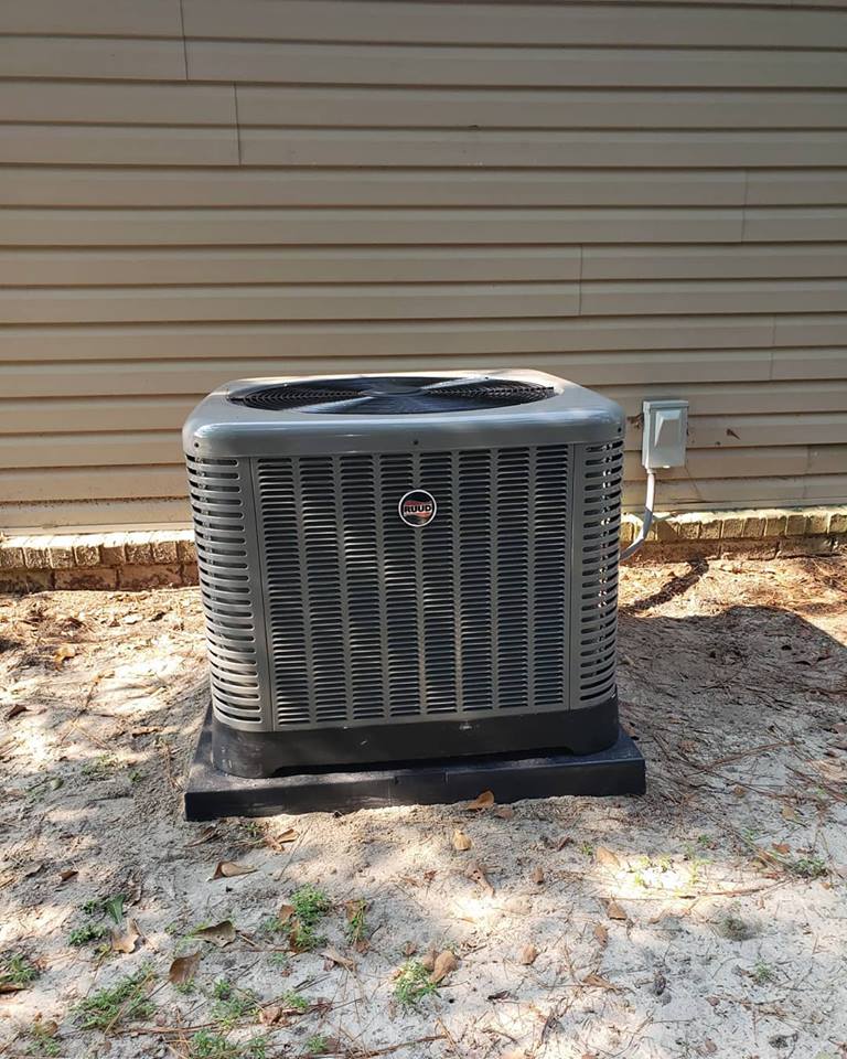 a large air conditioner is sitting in the dirt in front of a house .