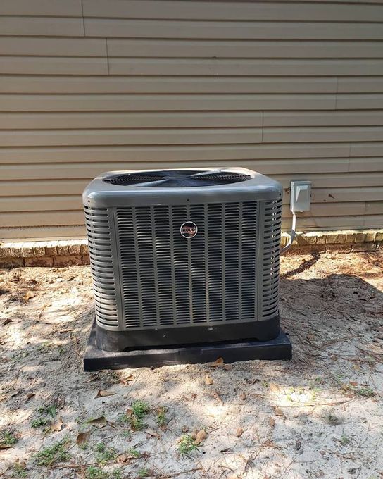 a large air conditioner is sitting in the dirt in front of a house .