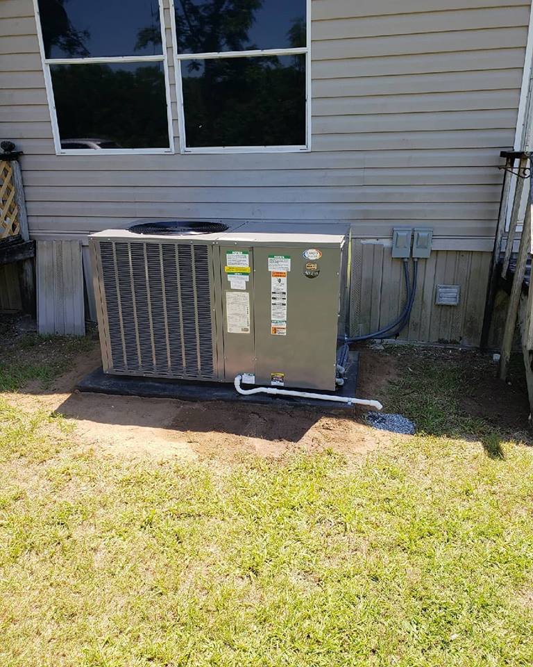 an air conditioner is sitting in the grass in front of a house .
