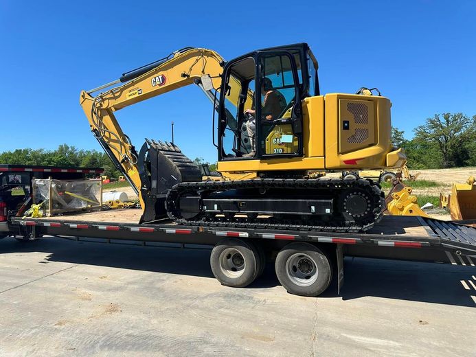 A yellow excavator is sitting on top of a trailer.