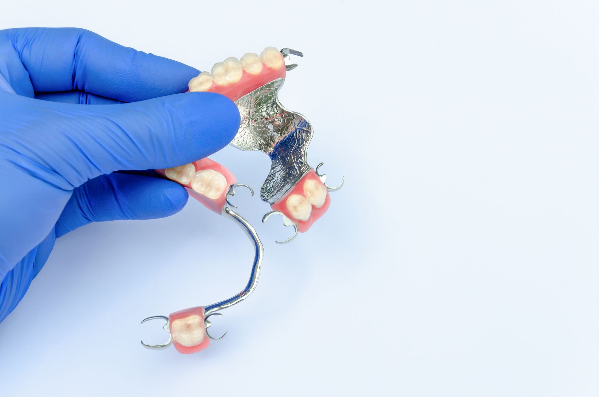 Model of teeth, showing upper and lower rows. White teeth set in pink gums, with a black background.