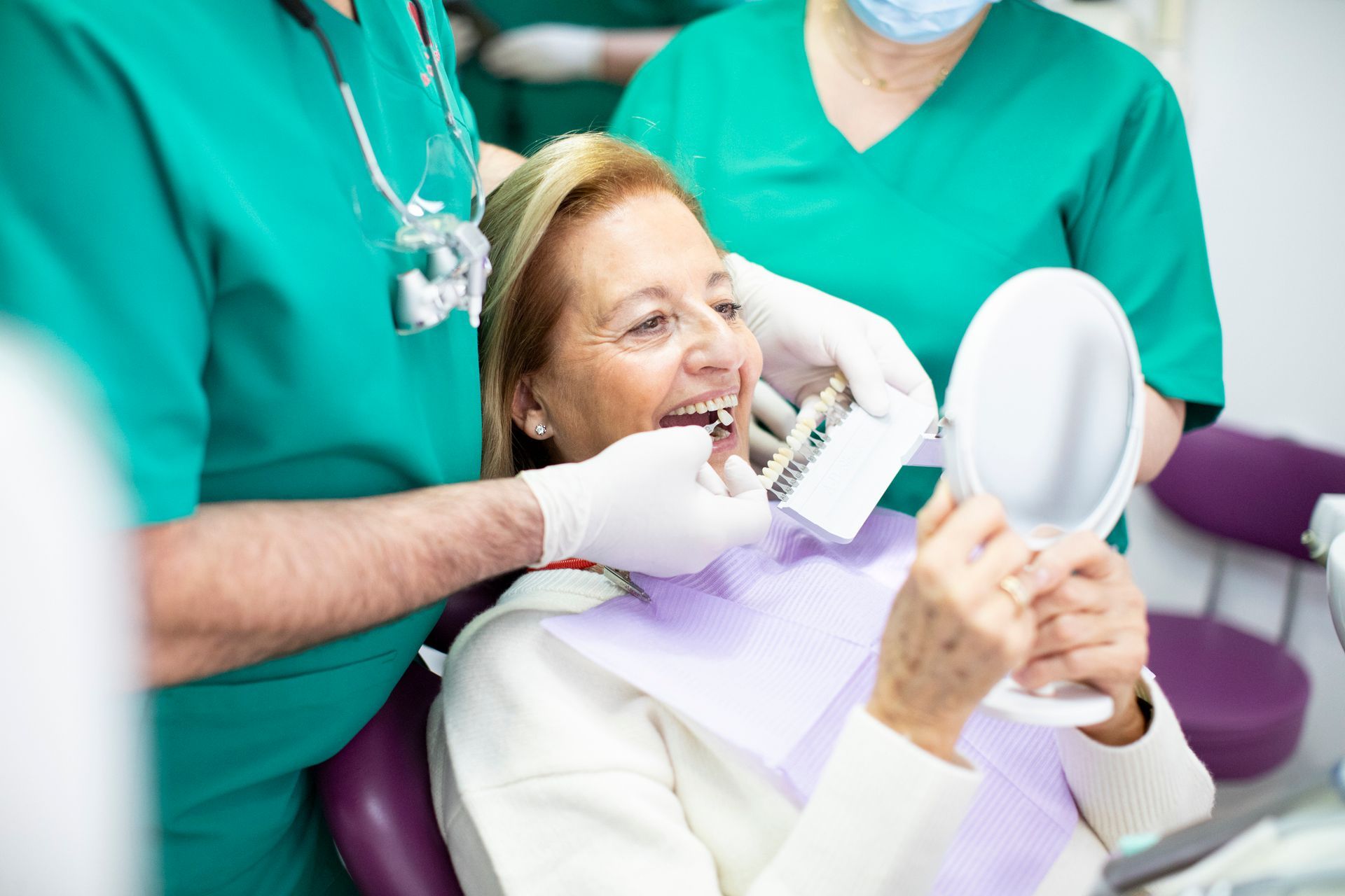 Dentists match tooth shade to a smiling elderly woman during a denture repair consultation. Dentists match tooth shade to a smiling elderly woman during a denture repair consultation.