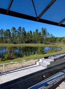 Covered outdoor seating overlooking a pond and trees on a sunny day