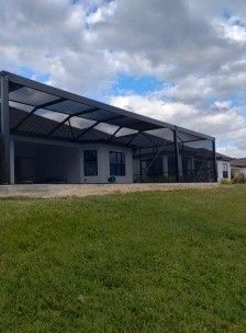 Modern building with large covered patio, grassy foreground, and cloudy sky