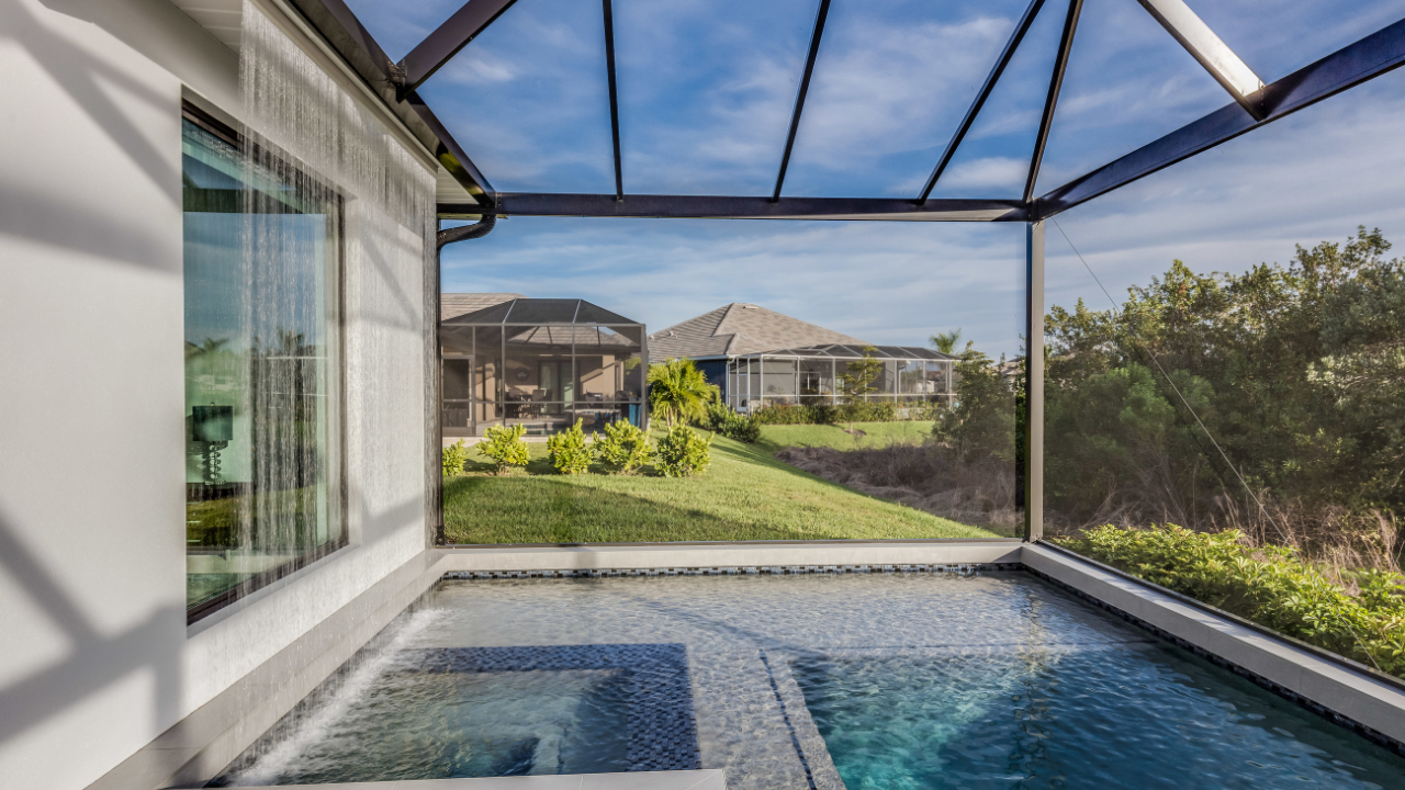 Covered patio with a small pool, overlooking a sunny backyard and houses beyond